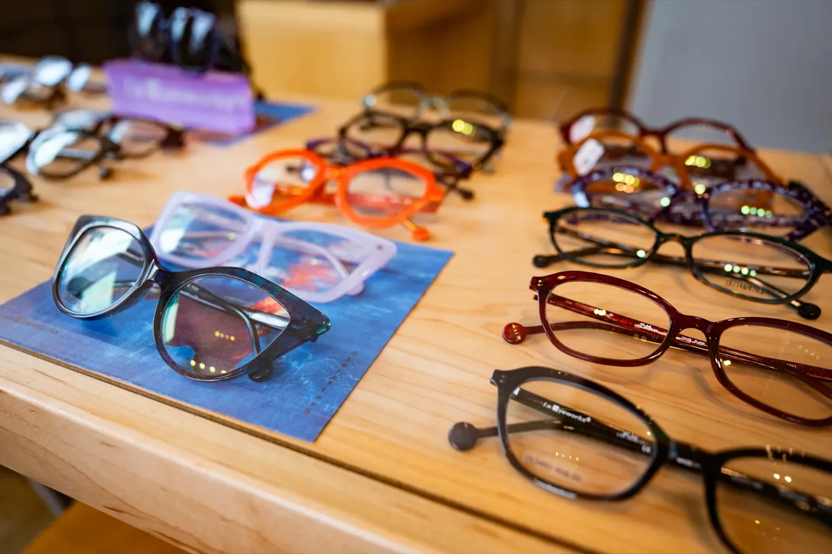 Designer eyeglass frames laid out on a wood display table at Voorthuis Opticians